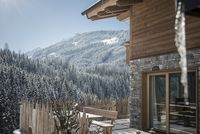 Winterlandschaft mit schneebedecktem Wald und Holzhütte mit Terrasse